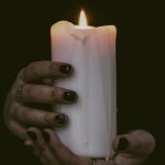 hands holding a white pillar candle