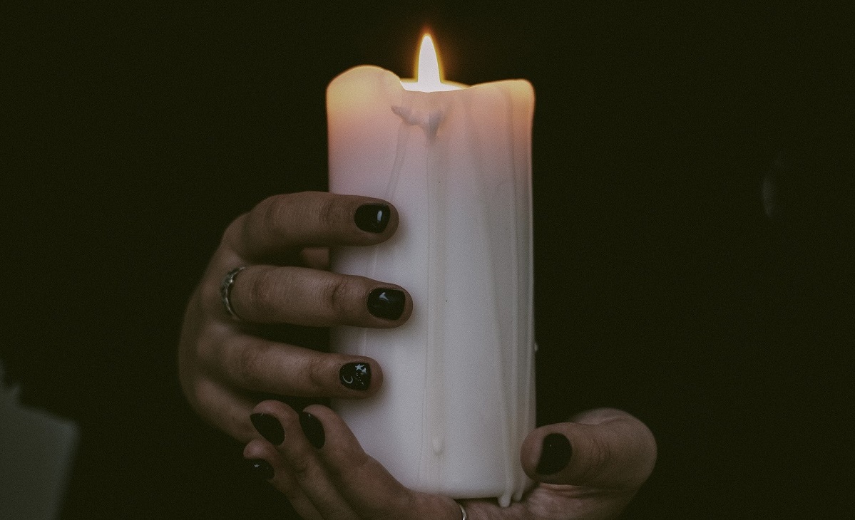 hands holding a white pillar candle