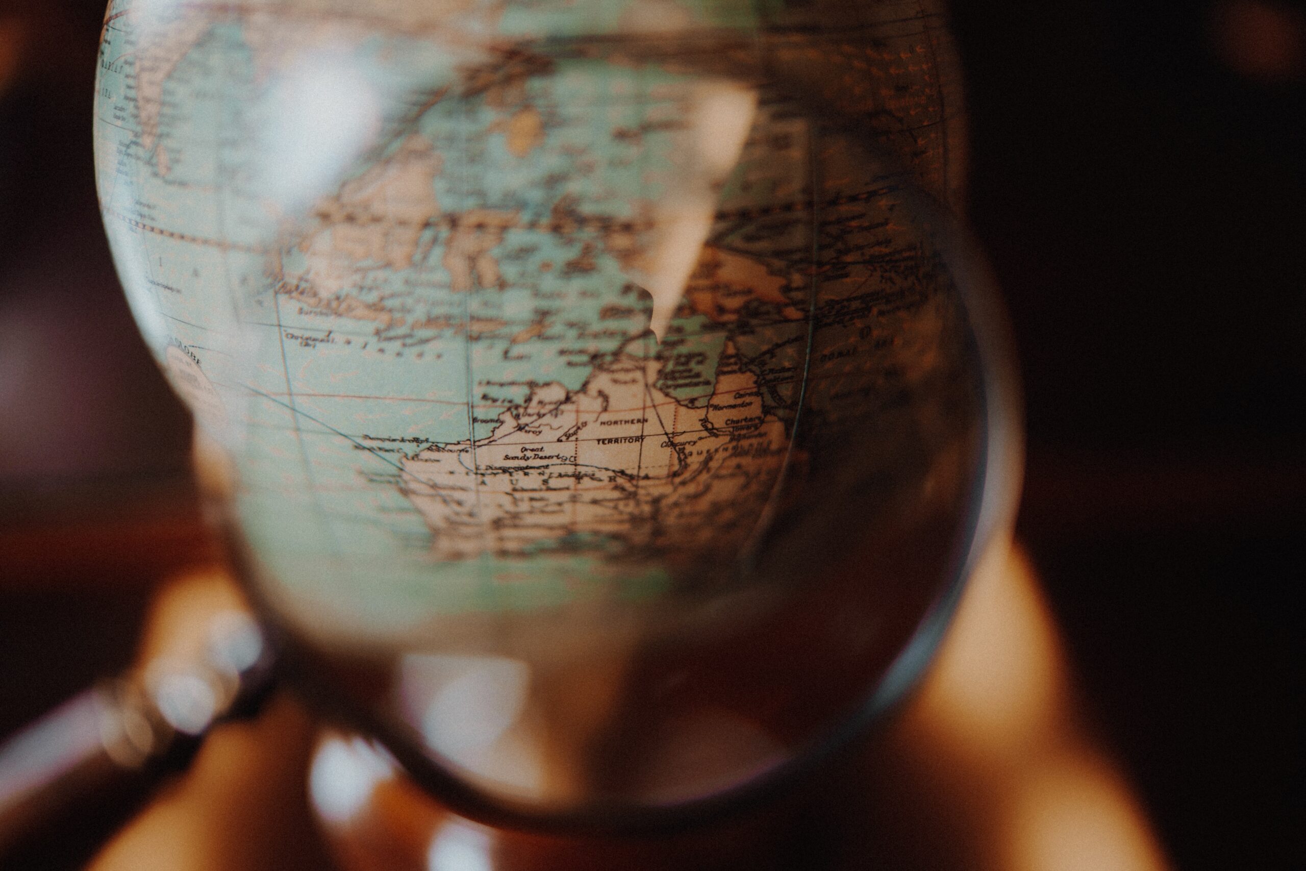 globe with a magnifying glass looking at Australia