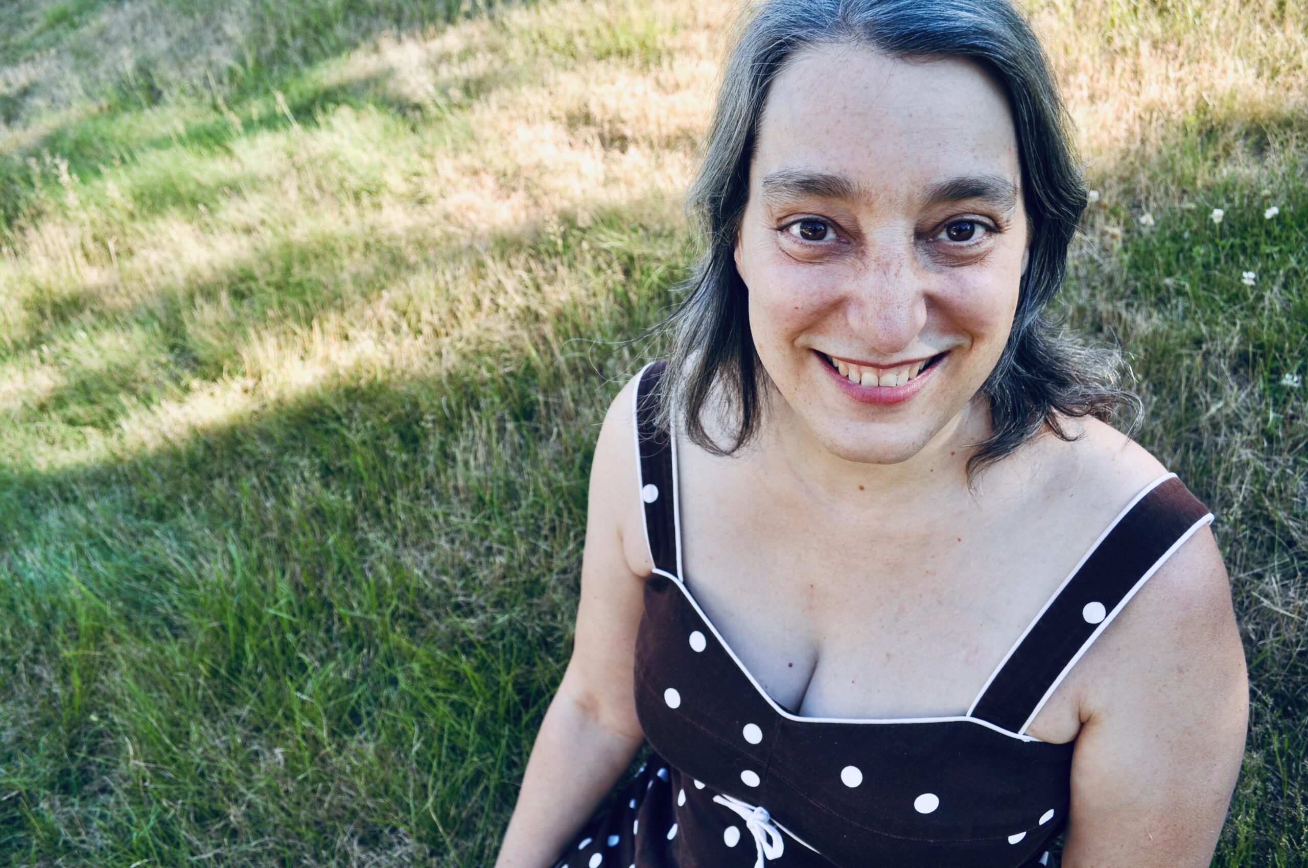 Alice Leibowitz sitting in the grass with a big, vivid smile